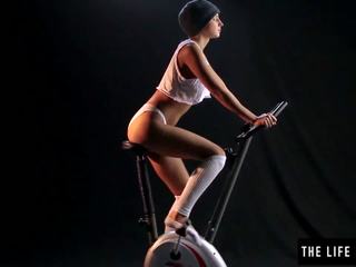 Gira suado jovem grávida a esfregar um exercise bike assento.